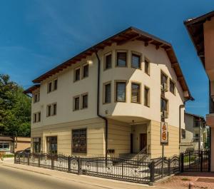 a large white house with a black fence at Grand Apartments-For Groups in Sarajevo