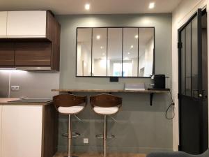 a kitchen with two stools at a counter with a mirror at Studio design proche Champs-Elysées in Paris