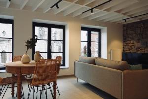 a living room with a couch and a table and chairs at Le Grand George - Résidence Le Cercle in Marche-en-Famenne