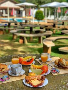 a table topped with plates of breakfast foods and orange juice at Camping e Pousada Paiol in Águas da Prata