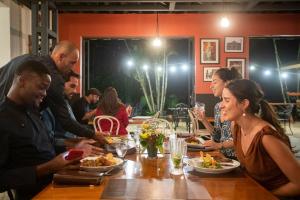 Eine Gruppe von Menschen, die an einem Tisch sitzen und Essen essen. in der Unterkunft Villa San Ignacio in Alajuela