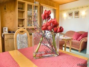 eine Vase mit roten Blumen auf einem Tisch in der Unterkunft Pension Landhaus Riedelstein in Drachselsried