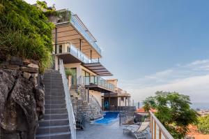 ein Haus auf einer Klippe mit einer Treppe und einem Pool in der Unterkunft Number 15 Ocean & City View Villas in Funchal