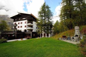 a large building on a hill with a green yard at Cervinia Apartment in Breuil-Cervinia