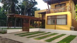 a yellow house with a wooden pergola at Conchas do Mar Residence in Itacaré