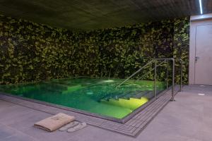 a swimming pool in a room with a green wall at Podere Vignanova Rooms & SPA in Castagneto Carducci