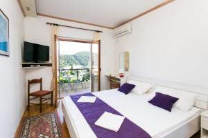 1 dormitorio con 1 cama grande y balcón en Apartments Petra, en Dubrovnik