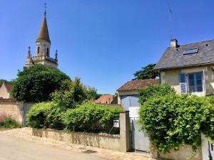 a house with a gate and a church in the background at "Côté cour, côté jardin" in Bonnes