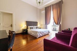 ein Schlafzimmer mit einem Bett und einem lila Sofa in der Unterkunft Gramsci Suites in Neapel