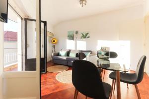 een woonkamer met een glazen tafel en zwarte stoelen bij Marques Balcony by Homing in Lissabon