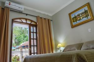 1 dormitorio con 1 cama y puerta a un balcón en Hotel Real São Lourenço, en São Lourenço