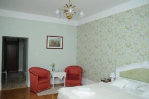 een slaapkamer met 2 rode stoelen en een bed bij Sophie Apartment in Oradea
