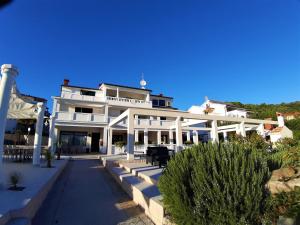 a large white building with a porch at Guesthouse Raffaello in Kampor