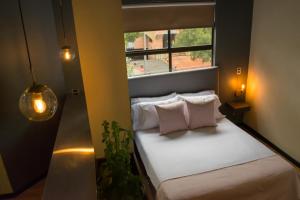 a small bedroom with a bed with a window at Soy Local Parque La 93 in Bogotá