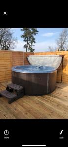 a hot tub sitting on a deck next to a fence at GROOMS COTTAGE OUTSIDE HOT TUB in Beith