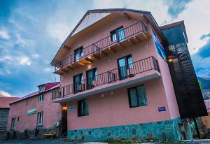 a pink building with balconies on the side of it at Soncho Kazbegi in Stepantsminda