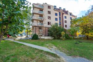 a building in a park with a path in front of it at CityHome Aparthotel in Sofia