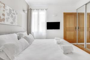 a white bedroom with a large white bed and a television at Pick A Flat's Apartments in Batignolles - Rue Biot in Paris