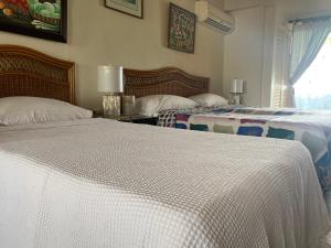 two beds in a hotel room with white sheets at Beach Vue Barbados in Bridgetown