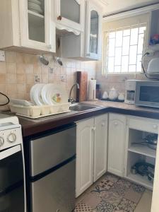 a kitchen with white cabinets and a sink and a microwave at Beach Vue Barbados in Bridgetown