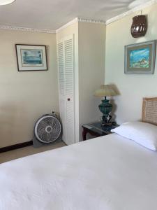 a bedroom with a white bed and a fan at Beach Vue Barbados in Bridgetown