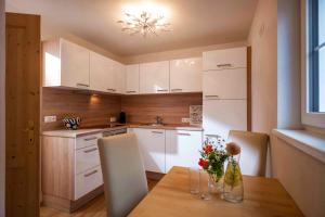 cocina con mesa de madera y armarios blancos en Chalet Schott en Kirchberg in Tirol