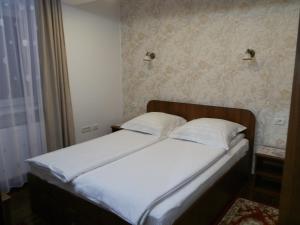 Garsoniera Strada Bucegi في سيبيو: سرير بشرشف ووسائد بيضاء في الغرفة