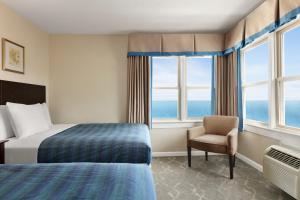 ein Hotelzimmer mit einem Bett, einem Stuhl und Fenstern in der Unterkunft Harrison Hall Hotel in Ocean City