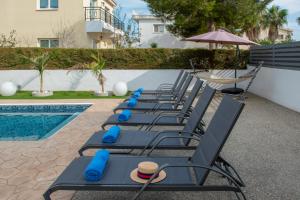 - une rangée de chaises longues à côté de la piscine dans l'établissement Villa Fortuna, à Ayia Napa