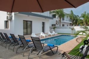 una piscina con sillas, una mesa y una sombrilla en Villa Fortuna, en Ayia Napa