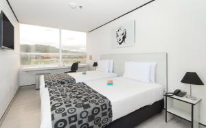 a hotel room with two beds and a window at Pop Art Hotel Tocancipá y Centro de Convenciones in Tocancipá