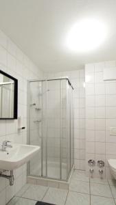 Un baño blanco con ducha y lavabo. en Innsbruck Apartment Nigler, en Innsbruck