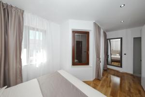 a white bedroom with a bed and a window at Villa Dalmatino in Pakoštane