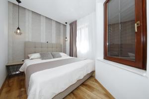 a white bedroom with a large bed and a window at Villa Dalmatino in Pakoštane