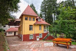 a yellow house with a bench in front of it at Clermont Sinaia in Sinaia