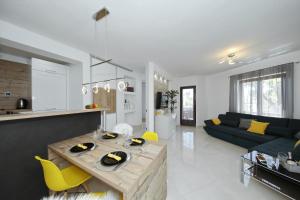 a kitchen and living room with a table and yellow chairs at Villa Dalmatino in Pakoštane