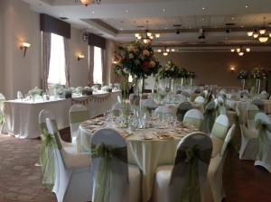 a banquet hall with white tables and chairs and flowers at Towers Hotel & Spa in Swansea
