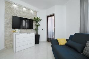 a living room with a blue couch and a tv at Villa Dalmatino in Pakoštane