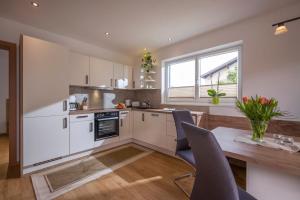 une cuisine avec des placards blancs et une table en bois dans l'établissement Ferienwohnung Thaler, à Itter