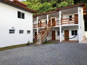 a white building with a staircase on the side of it at Pousada Recanto das Margaridas in Boicucanga