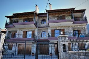 una antigua casa de piedra con balcones y una valla en Mainades House, en Vitina