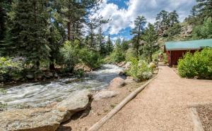 a river next to a building next to a forest at Swiftcurrent Lodge in Estes Park