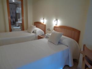 a hotel room with two beds and a bathroom at Hostal El Retiro in Almoradí