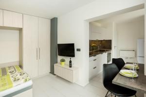 a kitchen with white cabinets and a dining room with a table at Apartmány Stožec - Stela Premium in Stožec