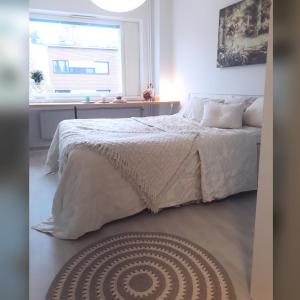 um quarto com uma cama com lençóis brancos e uma janela em Matkustajakoti Evakko em Seinäjoki