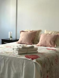 uma cama com almofadas cor-de-rosa e toalhas em Departamento Ideal Super Centrico!! em Mendoza