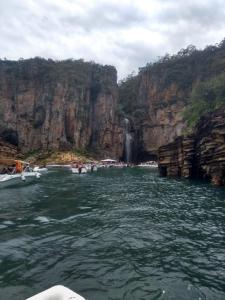 a group of boats in the water near a waterfall at casa da Roberta in São José da Barra