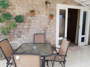 une table et des chaises en verre sur la terrasse dans l'établissement Escolha flat família com cozinha ou suítes separadas e independentes, à Conservatória