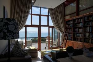 a living room with a book shelf and a large window at Shaloha Guesthouse on Supertubes in Jeffreys Bay