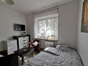 sypialnia z łóżkiem, krzesłem i oknem w obiekcie Krakow Centrum Gurgacza Apartments w Krakowie